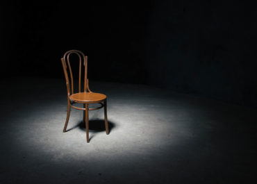 Lonely chair in the spot of light on black background at empty room