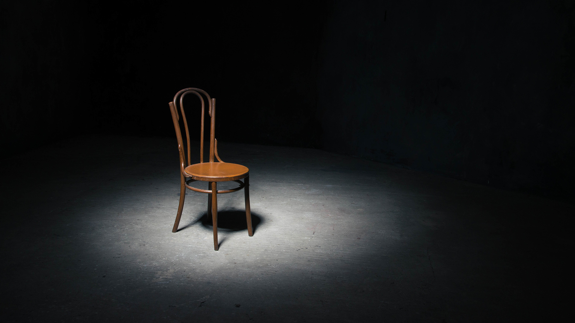Lonely chair in the spot of light on black background at empty room